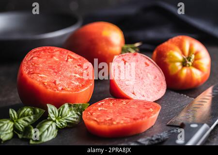 Sliced bull heart tomatoes on black table. Stock Photo