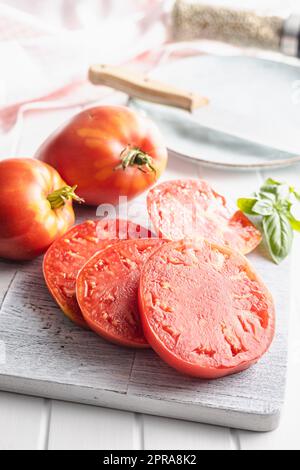 Sliced bull heart tomatoes on cutting board. Stock Photo