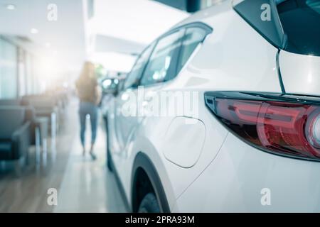 Closeup tail light of white SUV car parked in luxury showroom. Car dealership office. Rear view new car in modern showroom. Car for sale. Automobile leasing and insurance. Dealer agent business. Stock Photo