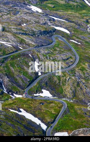 Green landscape with snow patches and a winding road seen in Norway Stock Photo