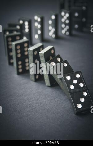 Black dominoes chain on dark table background Stock Photo