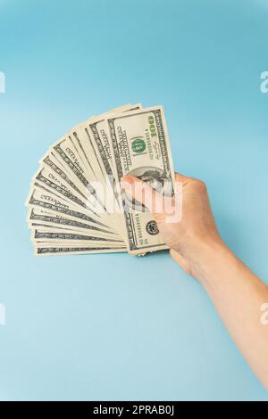 Female hands holding 100 dollar bills isolated on blue background. Stock Photo