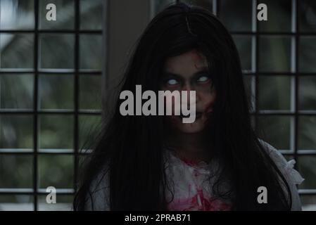 Female zombie in blood devil is scary she haunted at the abandoned building Stock Photo