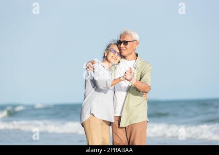 Happy Asian senior man and woman couple smile dancing resting relax on the beach Stock Photo