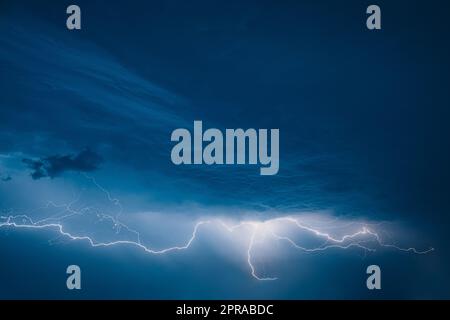 Bright Lightning On Blue Night Sky During Hunderstorm Stock Photo