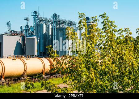 Set of train tanks next to plant for grain processing Stock Photo