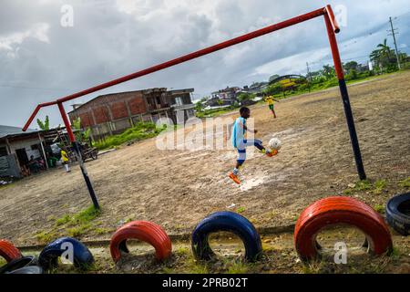 Afro-Colombian boys drill shooting during a football training session on a dirt playing field in Quibdó, Chocó, Colombia. Stock Photo