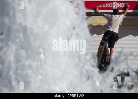 Malaga, Spain. 26th Apr, 2023. A worker is seen placing a banner at 'Plaza de la Marina' square amid an unusual heat wave. Spain is experiencing an unusual episode of high temperatures in April, months before the beginning of summer. According to the Spanish State Meteorological Agency, temperatures of over 35 degrees will be reached in most of the country. (Credit Image: © Jesus Merida/SOPA Images via ZUMA Press Wire) EDITORIAL USAGE ONLY! Not for Commercial USAGE! Stock Photo