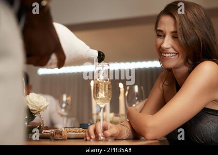 Fill it to the top please. an unrecognizable man standing and pouring champagne into a glass for a friend during a dinner party. Stock Photo
