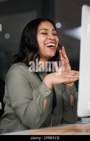 We work around the clock to keep our clients satisfied. a woman wearing a headset while looking at her desktop in a call centre. Stock Photo