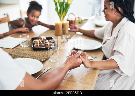 Blessing the meal that has been prepared. an unrecognizable family holding hands during prayer time at home. Stock Photo