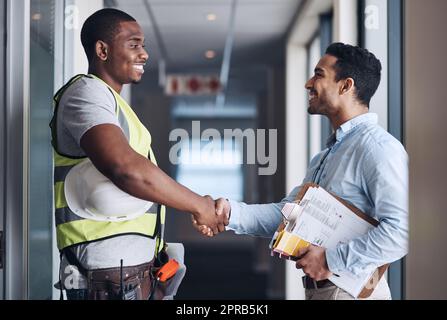 Thank you for trusting us with your renovations. two young architects standing together and shaking hands after a discussion about the room before they renovate. Stock Photo