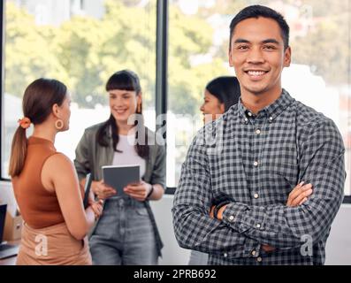 Im on stage, got a M in my minimum wage. Portrait of a young businessman at the office standing in front of his colleagues having a meeting in the background. Stock Photo