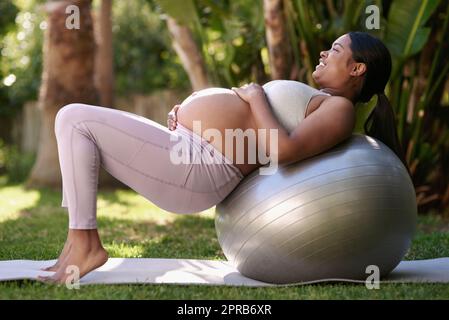 I want to feel fit and strong for delivery. a pregnant woman working out with a stability ball outside. Stock Photo