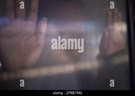 Depression got her feeling trapped. an unrecognizable womans hands pressed up against the window of a train. Stock Photo