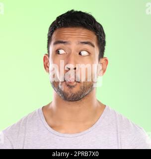 My lips are sealed. a handsome young man making a face against a green background in studio. Stock Photo