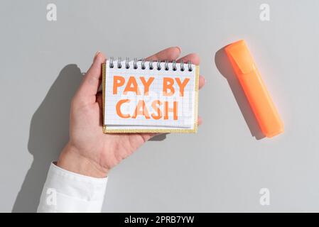 Conceptual display Pay By Cash. Business concept Customer paying with money coins bills Retail shopping Woman Holding Notepad With Important Message On Office Desk With Marker. Stock Photo