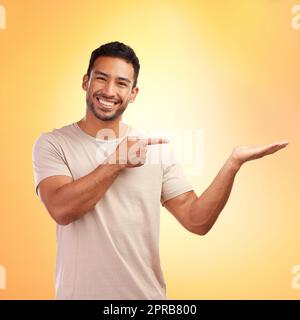 I think youll find this very useful. a young man pointing at copy space against a yellow background. Stock Photo