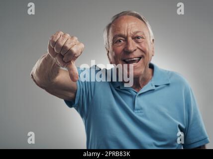 Id give that product a thumbs down definitely. a happy older man giving the thumbs down in a studio against a grey background. Stock Photo