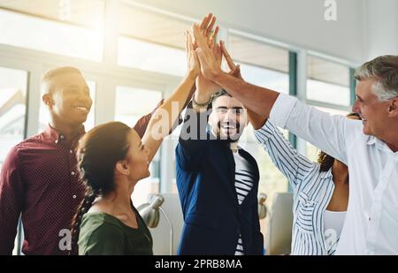 Corporate businesspeople celebrate success in an office. Passionate people feeling motivated, confident and cheerful. Excited, smiling and diverse professional group happy with their big win. Stock Photo