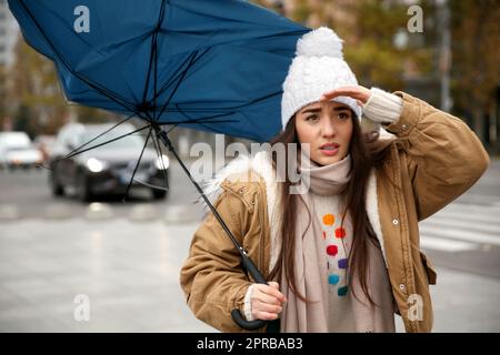 Woman with blue umbrella caught in gust of wind on street Stock Photo