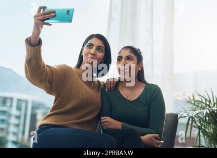 Silly selfies with my sister. two young women taking a selfie together while sitting at home. Stock Photo