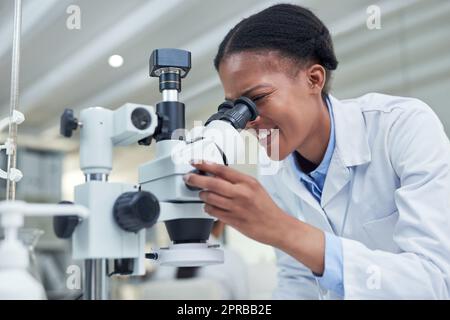 Its all about the nature of discovery and development. a young scientist using a microscope in a lab. Stock Photo
