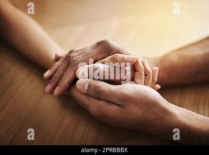 Holding hands in support and comfort, showing love, care and consoling a friend. Two people together in unity, solidarity and trust, showing kindness, hope and faith while helping and bonding closeup Stock Photo