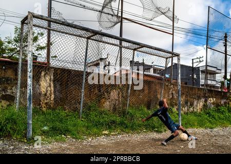 A young Afro-Colombian goal keeper saves the shot during a football training session on a dirt playing field in Quibdó, Chocó, Colombia. Stock Photo