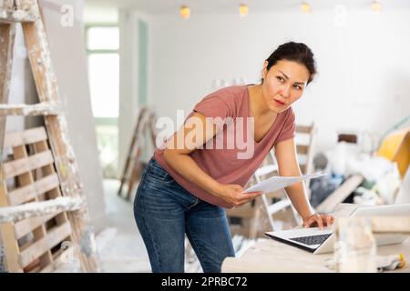 Woman construction manager checking project documentation, using laptop Stock Photo