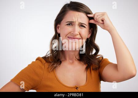 How much energy is left. Studio shot of a young woman gesturing a small size with her hand against a white background. Stock Photo