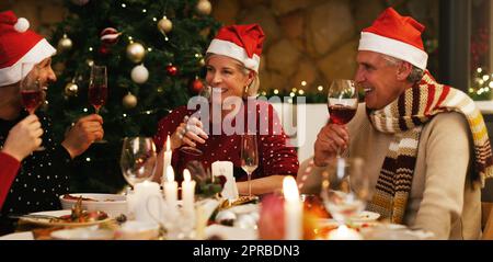 Friendship is more priceless than any present under the tree. a happy group of friends having Christmas lunch together at home. Stock Photo