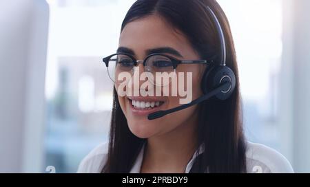 Offering the right advice to her clients. a young businesswoman wearing a headset while working in an office. Stock Photo