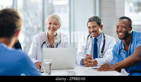 Doctors, medical professionals and healthcare workers with laptop talking, meeting or planning medicine treatment in hospital. Diverse group of happy frontline colleagues researching or brainstorming Stock Photo