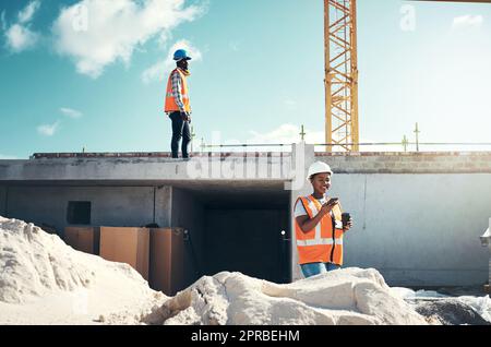 Back to constructing but first coffee. a young woman using a smartphone on a coffee break at a construction site. Stock Photo