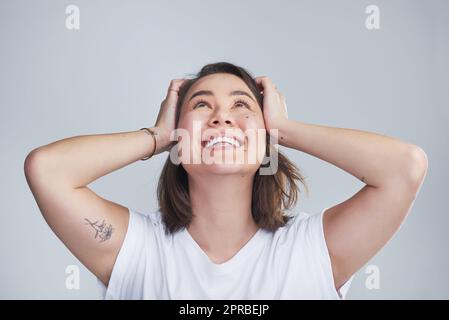 Look for the good in everything. a beautiful young woman posing against a grey background. Stock Photo