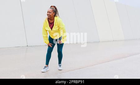Sport African senior woman taking breath before run training in the city - Elderly healthy lifestyle Stock Photo
