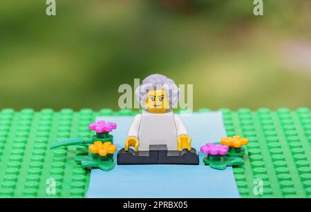 Active senior woman practicing yoga outdoors in nature. Ageing better healthy habits concept illustrated with Lego minifigure. Stock Photo