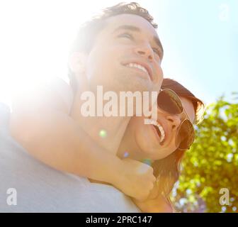 Living a life filled with love. Close up of happy couple outside who are embracing with the sun behind them. Stock Photo