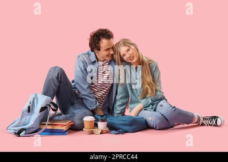 Teenage couple sitting on pink background Stock Photo