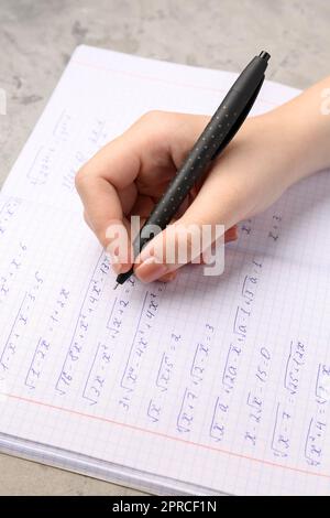 Woman writing maths formulas in copybook with pen, closeup Stock Photo