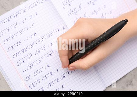 Woman writing maths formulas in copybook with pen, closeup Stock Photo