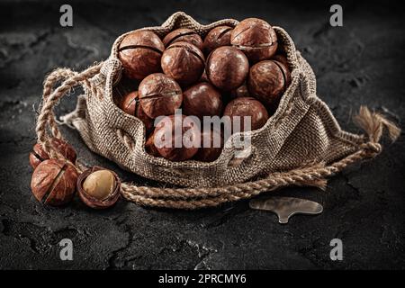 Opened Full Of Macadamia Nuts Burlap Bag On Dark Background Stock Photo