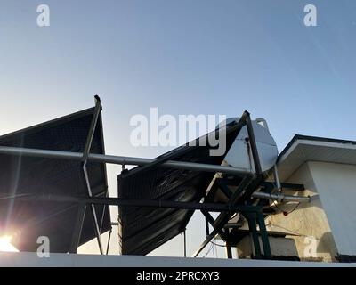 View of the roof of a building in a warm tropical country with solar panels and a water tank on the roof. Energy efficient eco-friendly technologies. Stock Photo