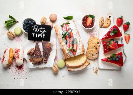 Candy bar of several kinds of colorful candies in glass jars decorated with  candles on white clothed table. Wedding or party concept Stock Photo - Alamy