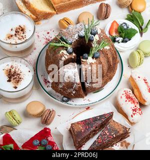 Dessert table with various of bundt cakes, pieces of cakes, sweets, cookies with fruit toppings on a white background. Top view. Stock Photo