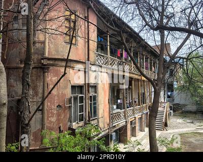 Beautiful old brown dilapidated three-story house with windows and balconies, slum terraces in the old urban area of Tbilisi. Georgia. Stock Photo