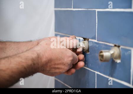 Unrecognizable senior plumber installing water tap in bathroom. Stock Photo