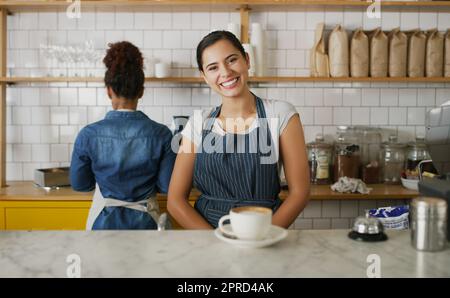 Its so nice to see you here again. Portrait of a young waitress standing behind a counter in a cafe. Stock Photo
