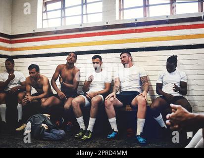 Theyre here because of their love for the sport. a group of handsome young rugby players sitting together in a locker room during the day. Stock Photo